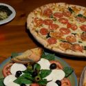 two pizzas, past and italian salad on table with wine at lombardi's pizza ocmd